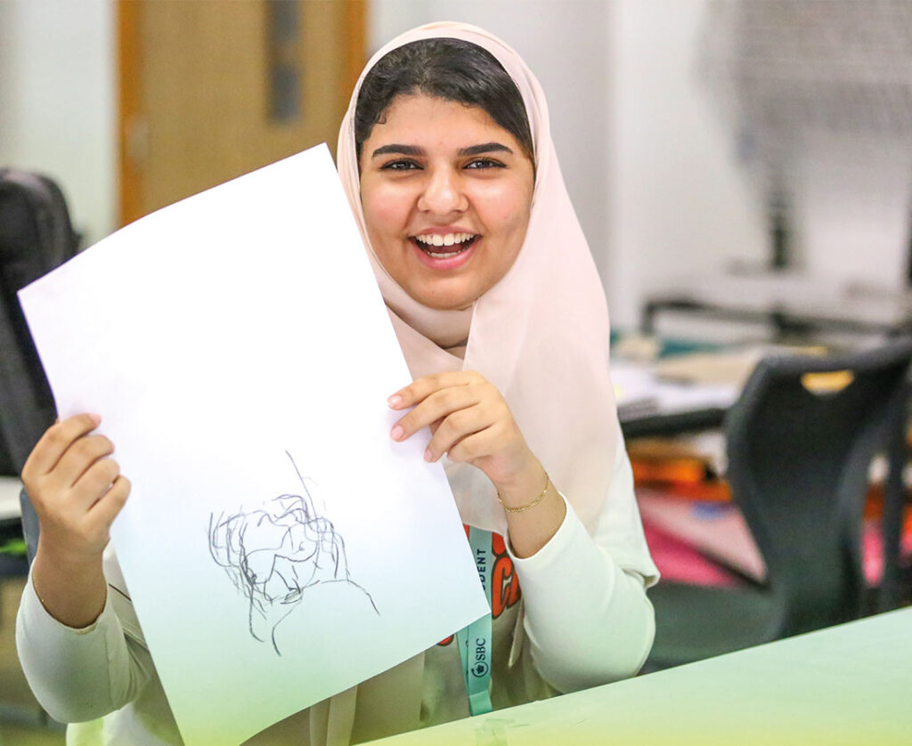 Happy-sbc-student-holding-artwork-at-cambridge-college